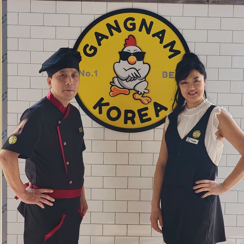 Sunju Lee and Chef Yangmo Kim under the Gangnam Korea sign in the Huntsville shop